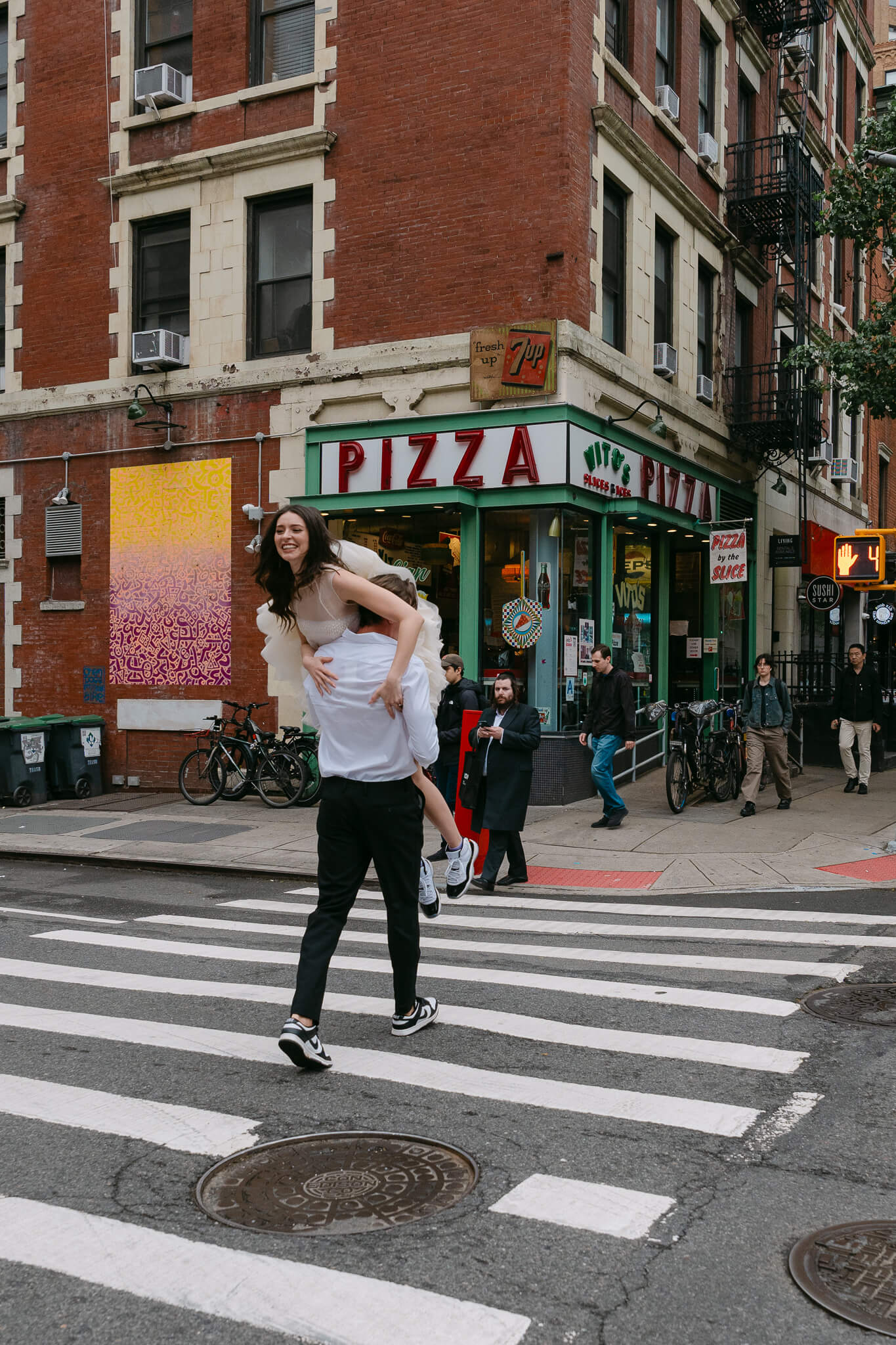 nyc hells kitchen engagement session fun photo ideas with man grabbing his girl over his shoulders and running across the street
